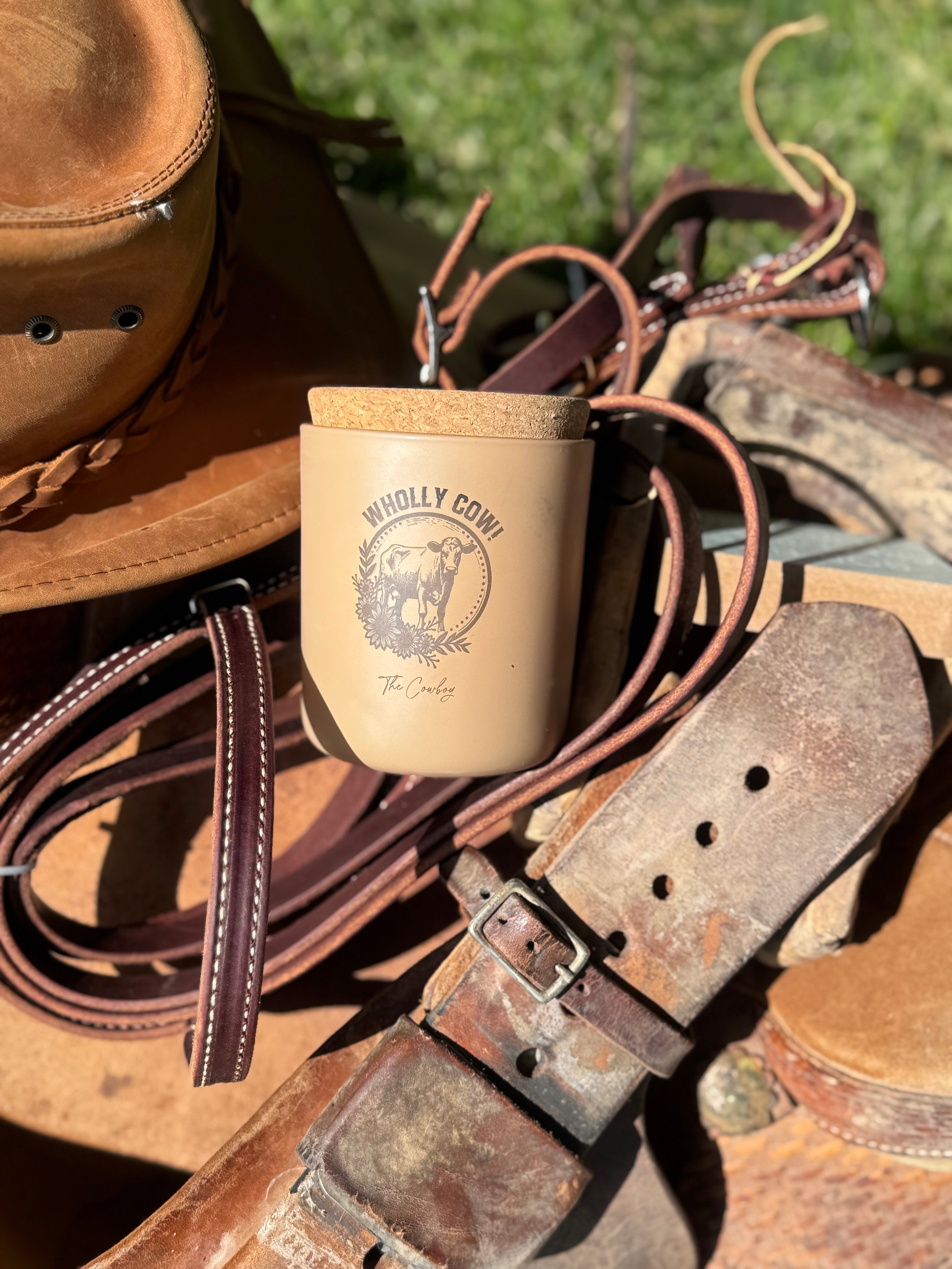 A tan candle sitting with a horse saddle and brown cowboy hat