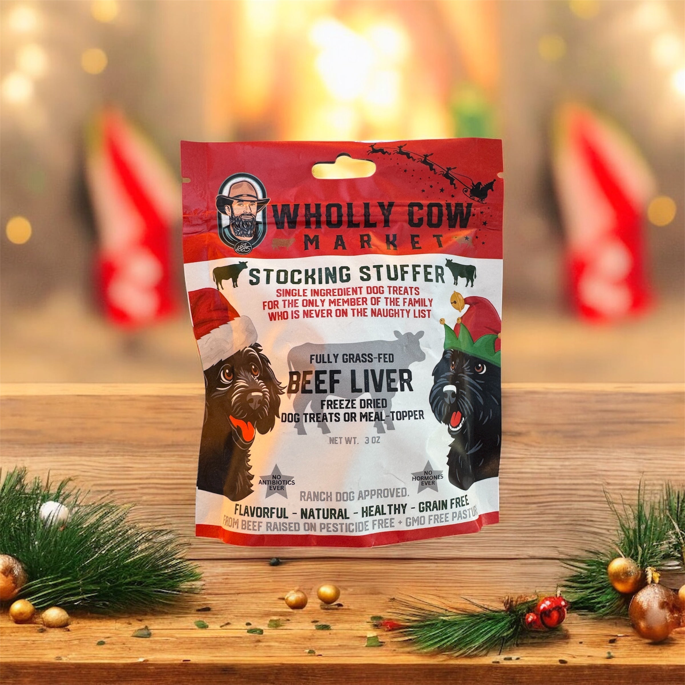 A Christmas bag of freeze-dried beef liver dog treats on a table with evergreen branches & ornaments